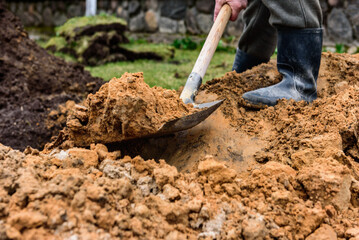 Earthworks, man digging trench using shovel.