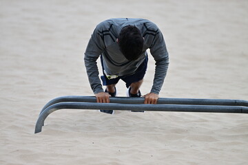 A young, sportive man doing push-ups on the beach of Benidorm-Spain.