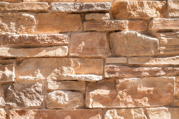exterior wall of non-uniform stones well placed in relief, of a house of brown and reddish colors