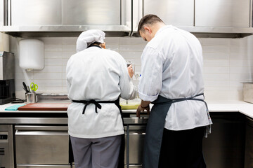 A couple of unrecognizable chefs are preparing a succulent menu in a restaurant kitchen.The woman...