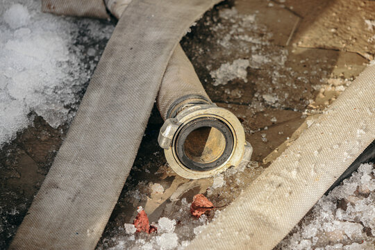 There is a fire hose with ice on the ground. Hose is bent and kinked