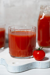 tomato juice in glasses on a white background, vertical closeup