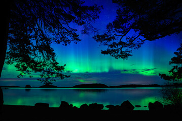 Northern light dancing over calm lake in north of Sweden.Farnebofjarden national park. - 774155164