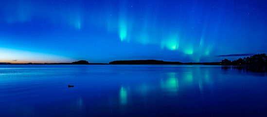 Northern light dancing over calm lake in north of Sweden.Farnebofjarden national park. - 774155189