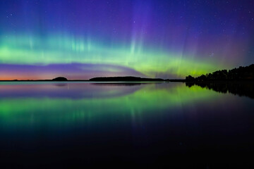 Northern light dancing over calm lake in north of Sweden.Farnebofjarden national park. - 774155355