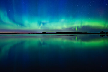 Northern light dancing over calm lake in north of Sweden.Farnebofjarden national park.