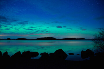 Northern light dancing over calm lake in north of Sweden.Farnebofjarden national park. - 774155757