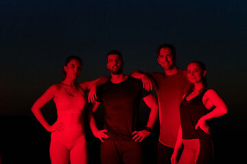 Diverse Athletes Unwind: Post-Marathon Rest Under Red Nighttime Glow.
