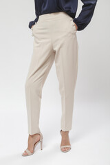 Female model wearing beige smart casual high rise trousers. Studio shot.
