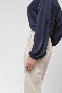 Serie of studio photos of young female model wearing dark blue silk satin blouse and cream trousers	