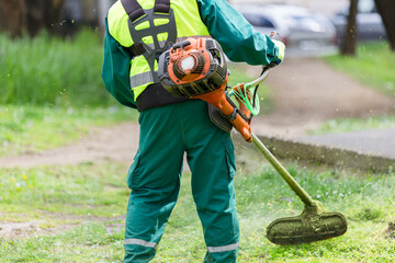Groundskeeper trimming grass with a weed whacker