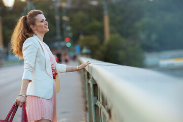 smiling stylish woman in pink dress and white jacket in city - 774166335