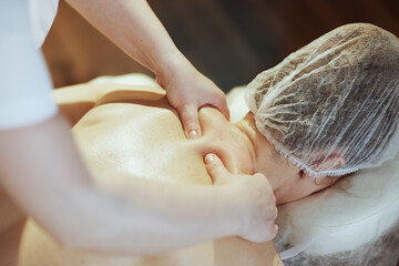 Closeup on medical massage therapist massaging clients neck