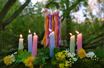 colorful magic candles and flowers in forest, natural background. Witch ritual for Beltane or Litha sabbat. Midsummer. Witchcraft, esoteric spiritual practice, divination. mysterious fairy scene - obrazy, fototapety, plakaty