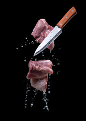 Flying pieces of pork with knife, isolated on black background