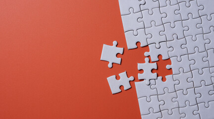 Unfinished white jigsaw puzzle on orange background with copy space. Business strategy teamwork and problem solving concept. - 774168903
