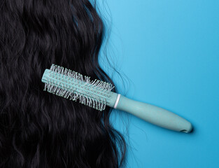 Close up of the texture of the shiny black human curly hair with comb on the blue background