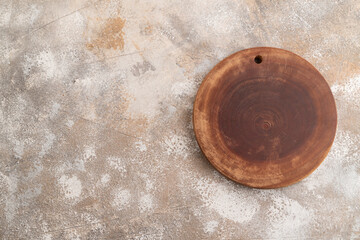 Empty round wooden cutting board on brown concrete. Top view, copy space