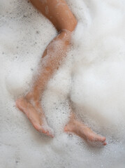 Woman legs in bath foam. Top view. Enjoying and relaxation