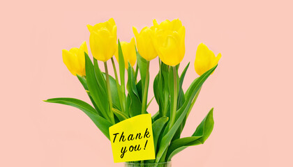 Beautiful bouquet of yellow tulip flowers in a vase and the inscription “Thank you.” Place for...
