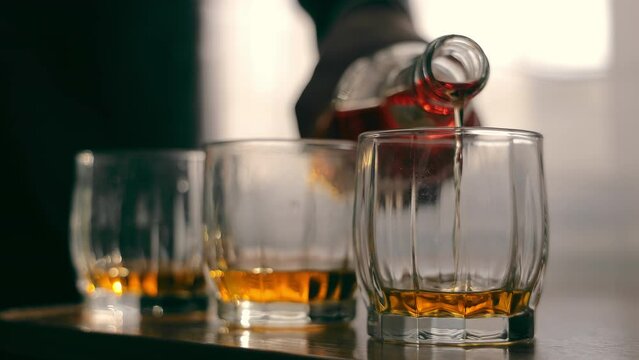 Whiskey Pouring Into Glasses, Close-up of amber whiskey being poured into glasses, with a warm glow.