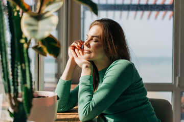 A woman sits in cafe near by window in bright sunlight from the window.