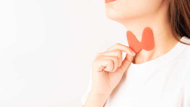 Female holding thyroid gland shape made from paper over her neck. Awareness of thyroid disorder includes goiter, hyperthyroid, hypothyroid, tumor or cancer. World Thyroid Day concept.