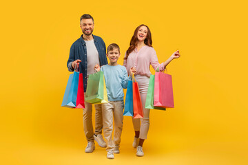 Family with shopping bags on yellow background