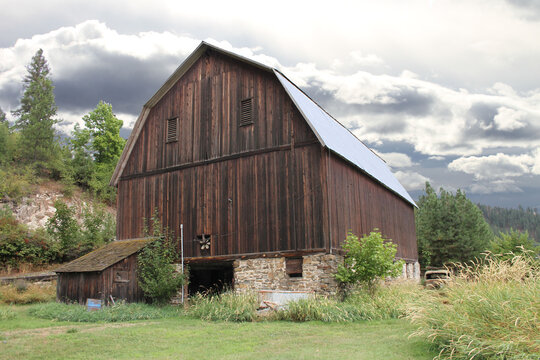 photograph of vintage dairy barn with old wood and a tin roof under a gray storm cloud