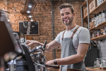Horizontal shot of attractive young man doing coffee for customers using professional machine....