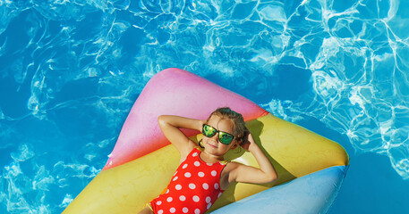 Cute happy girl in swimming resort pool - colorful vacation concept.