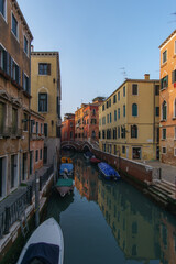 Typical narrow canal surrounded by colorful building facades with boats in Venice, Veneto, Italy
