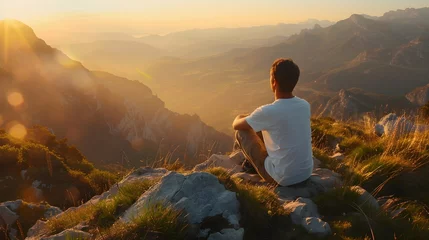 Gordijnen a man sitting on the top of a mountain at sunrise © TINA