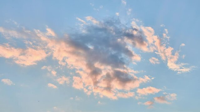 Beautiful picturesque clouds in blue sky, which is illuminated by setting sun.