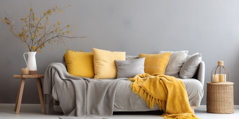 Yellow blanket and pillows on grey sofa in modern home interior with gray walls