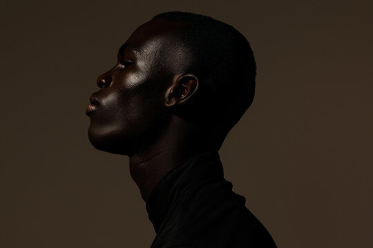 A mysterious silhouette of a man's profile presents a strong and contemplative stance against a warm brown backdrop
