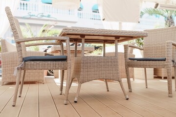 Wicker furniture tables in the open air are waiting for visitors. The interior of the restaurant in the open air. Empty tables of street cafe.