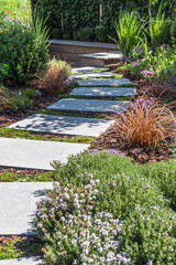 Path with large stone slabs through a beautifully planted garden