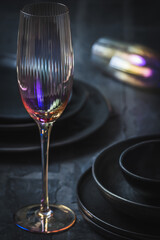 Pink shimmering champagne glass and black stoneware on a rustic black table, vertical