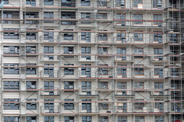 A multistory residential building under construction, enveloped in scaffolding, with a clear view of the work in progress against an overcast sky.