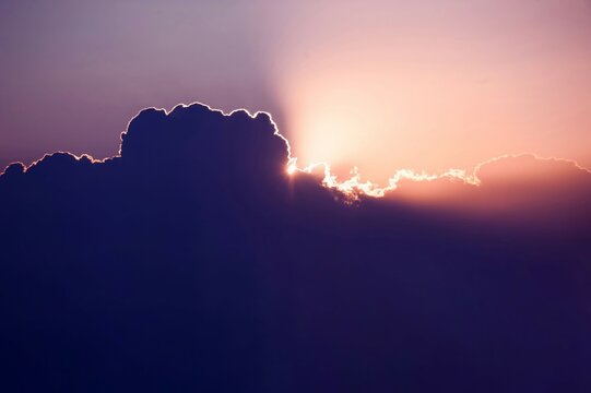 Every cloud has a silver lining. Sun rises over cumulus clouds its light rays breaking cover above the heavens