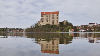Historical Plumlov castle from 17th century and reflection on the surface of the pond in Prostejov district in Czech republic. Cloudy smoke fog air pollution sky. - obrazy, fototapety, plakaty