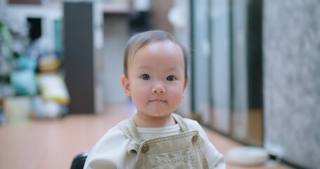 A baby toddler child is looking at the camera with a smile on its face and spit saliva from her...
