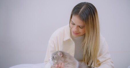 Portrait cute pretty young beautiful woman talking stroking cute little fluffy cat in living room, Relationship between pets and people. fluffy cat lying on her pet owner