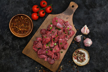 Raw organic meat beef or lamb with garlic, pepper spice on wooden board. Top view with copy space.