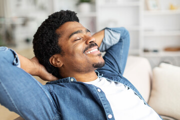 Black Man Relaxing on Couch With Hands Behind Head