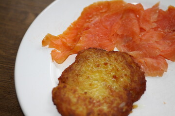 potato pancakes, grated biscuits with salmon, served on a white plate,
