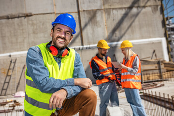 Construction site manager standing  wearing safety vest and helmet, thinking at construction site. Young architect watching construction site with confidence.
