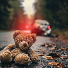 teddy bear on the road with car crash in the background