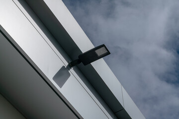 modern led street lamp on new construction with flat roof and metal facade, roof of a house,...